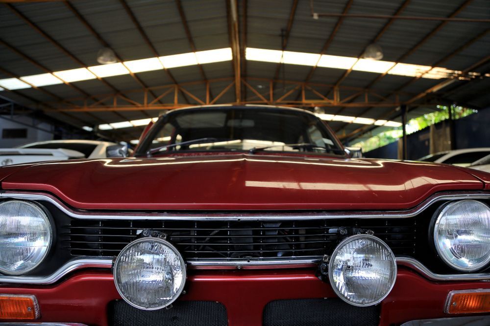 Front view of a red vintage car with chrome trim and round headlights in a garage