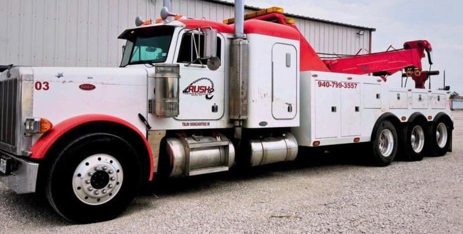 Man kneeling by blue pickup truck, appearing to work on the tire.