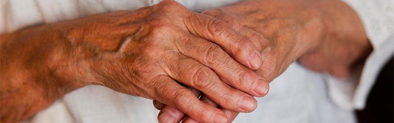 Image of an elderly man holding his knuckles in pain from osteoarthritis
