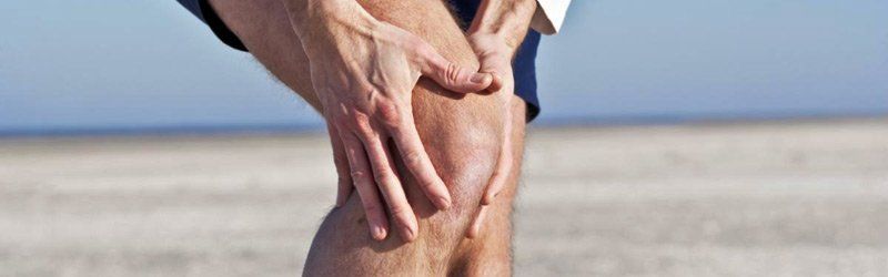 Image of a man holding his knee in pain