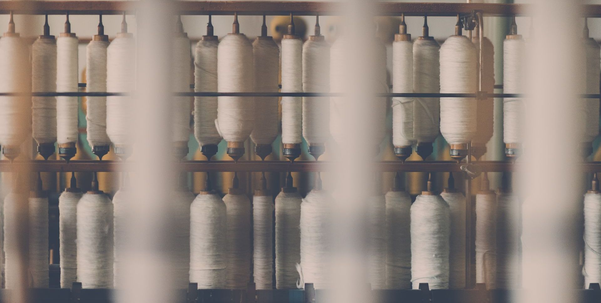 a bunch of spools of thread hanging on a rack