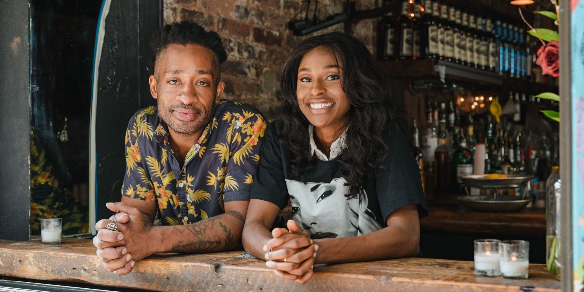 man in hawaiian shirt and woman at bar