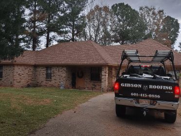 Gibson Roofing truck parked in driveway of home