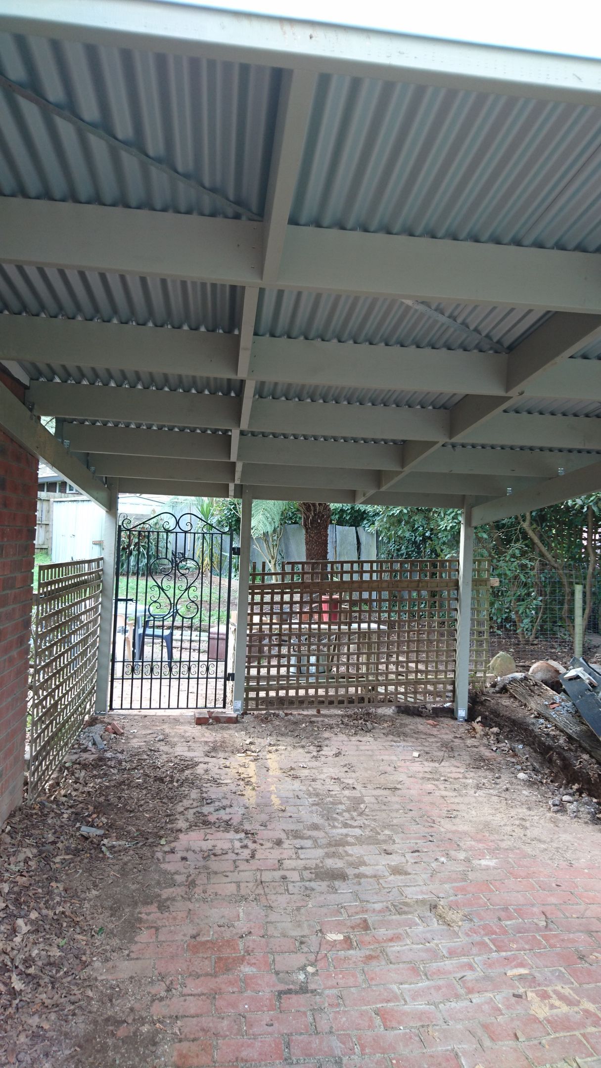 a carport with a fence and a car parked underneath it .