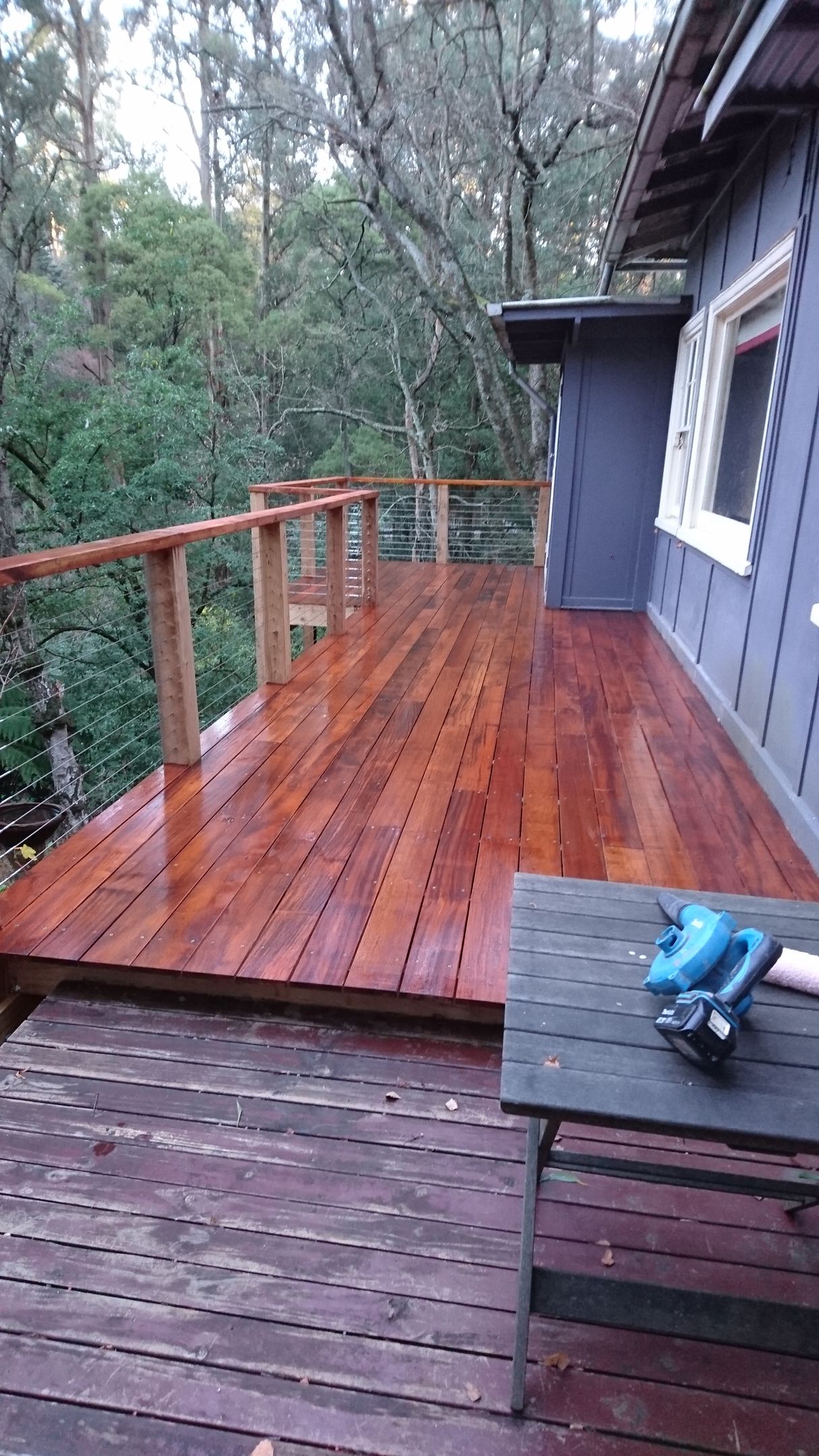 a wooden deck with a table and trees in the background .