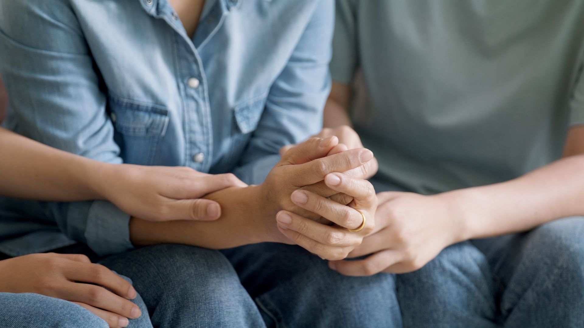 Two people sitting close together, holding hands on a couch