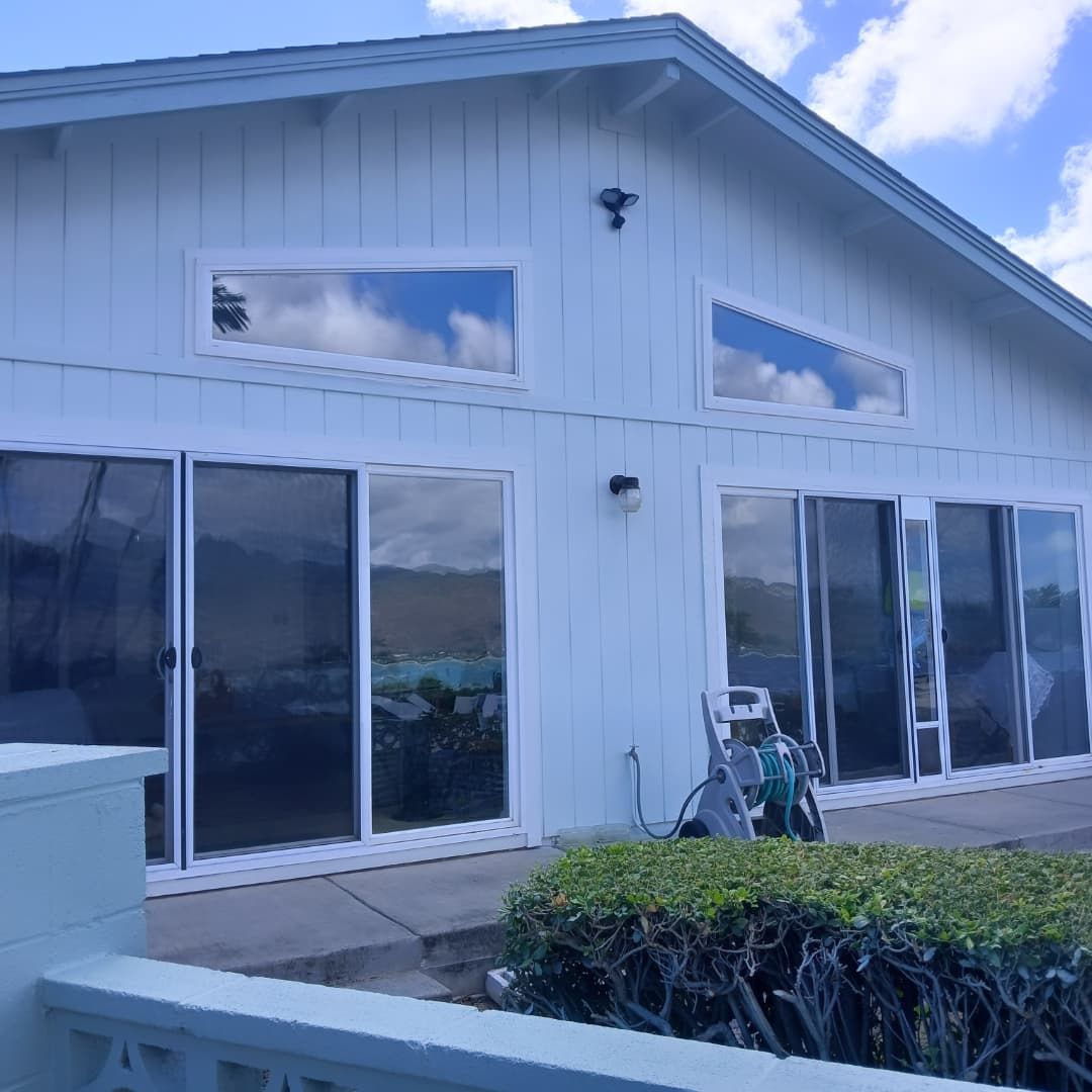 Light blue house with large sliding glass doors and rectangular windows. A pressure washer sits outside on a concrete patio.