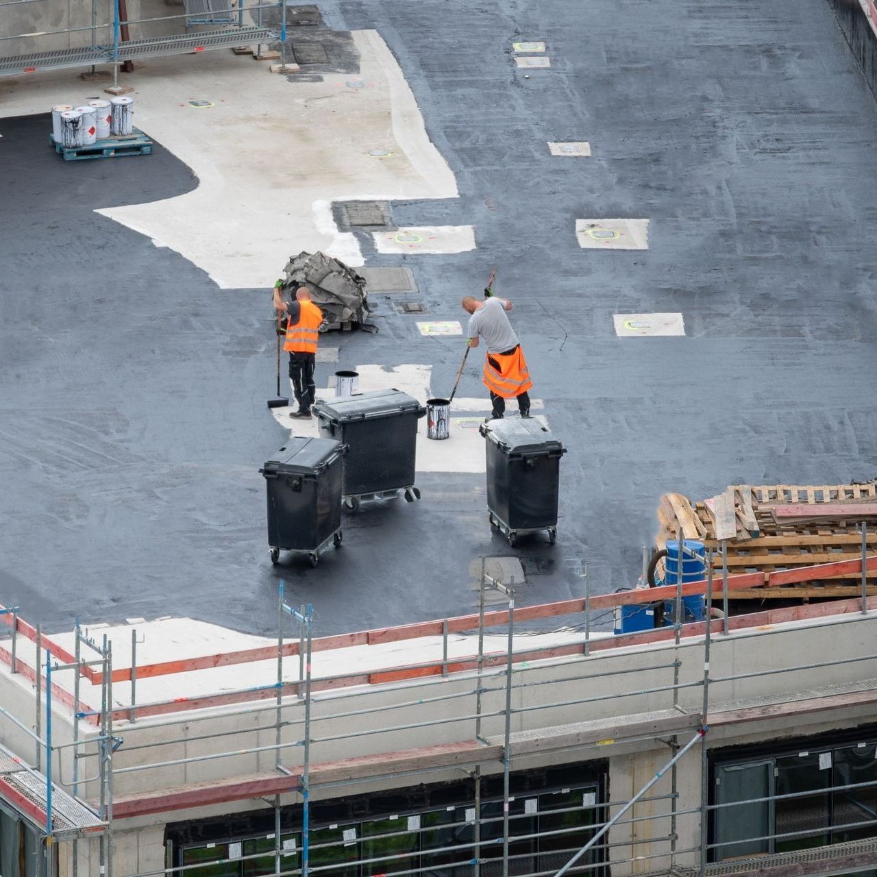 A group of construction workers are cleaning the roof of a building.