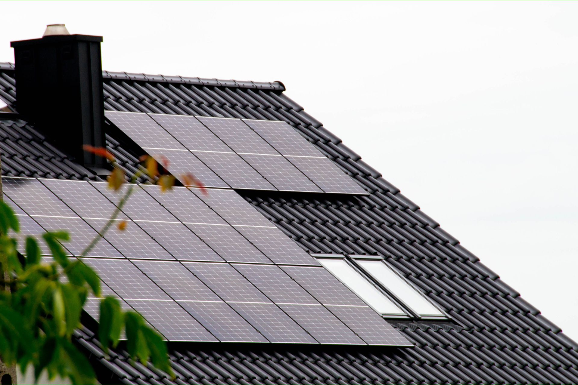 Solar panels on a dark tiled roof, chimney, and skylights visible.