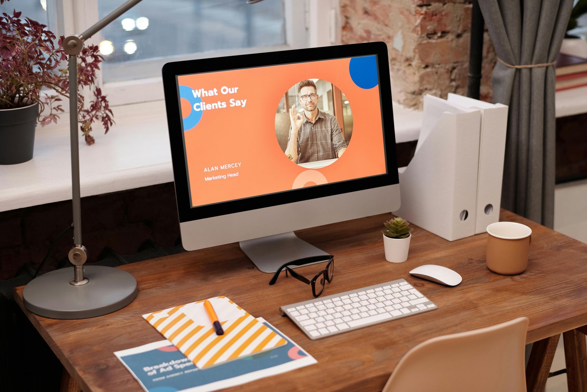 Ordinateur de bureau sur un bureau en bois avec clavier, souris, dossiers et tasse à café. Une présentation avec la photo d'une personne s'affiche à l'écran.