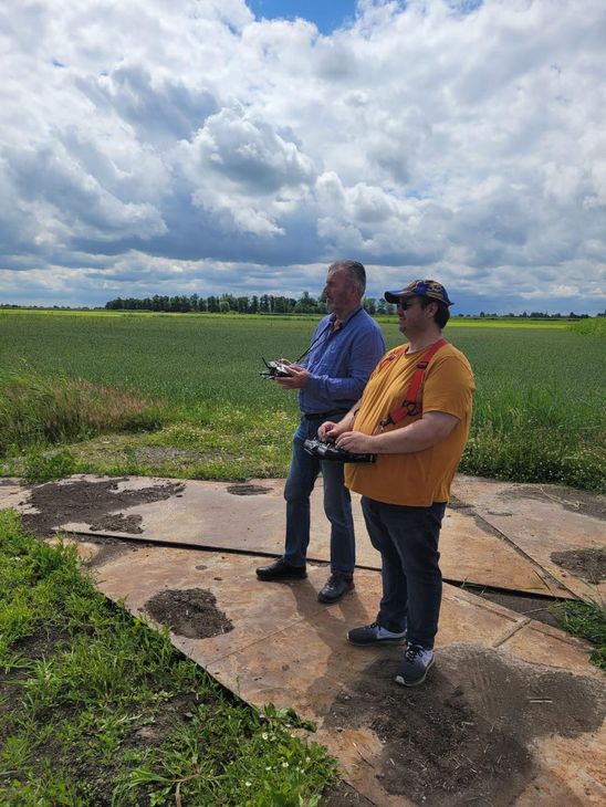 Twee mannen staan ​​in een veld met afstandsbedieningen in hun handen.