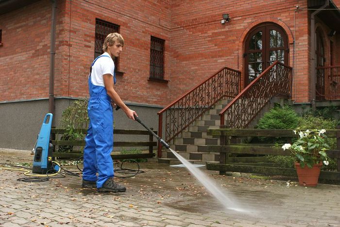 a woman in blue overalls is using a water hose