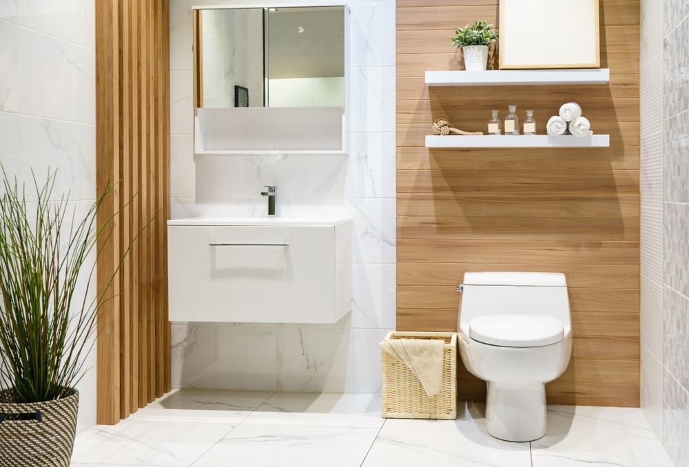 Modern white bathroom with floating vanity, toilet, wood accent wall, shelves, mirror, and potted plant — Hinch Plumbing In Breakwater, VIC