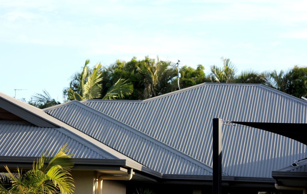 Two gray corrugated metal roofs with trees behind them under a clear blue sky — Hinch Plumbing In Breakwater, VIC
