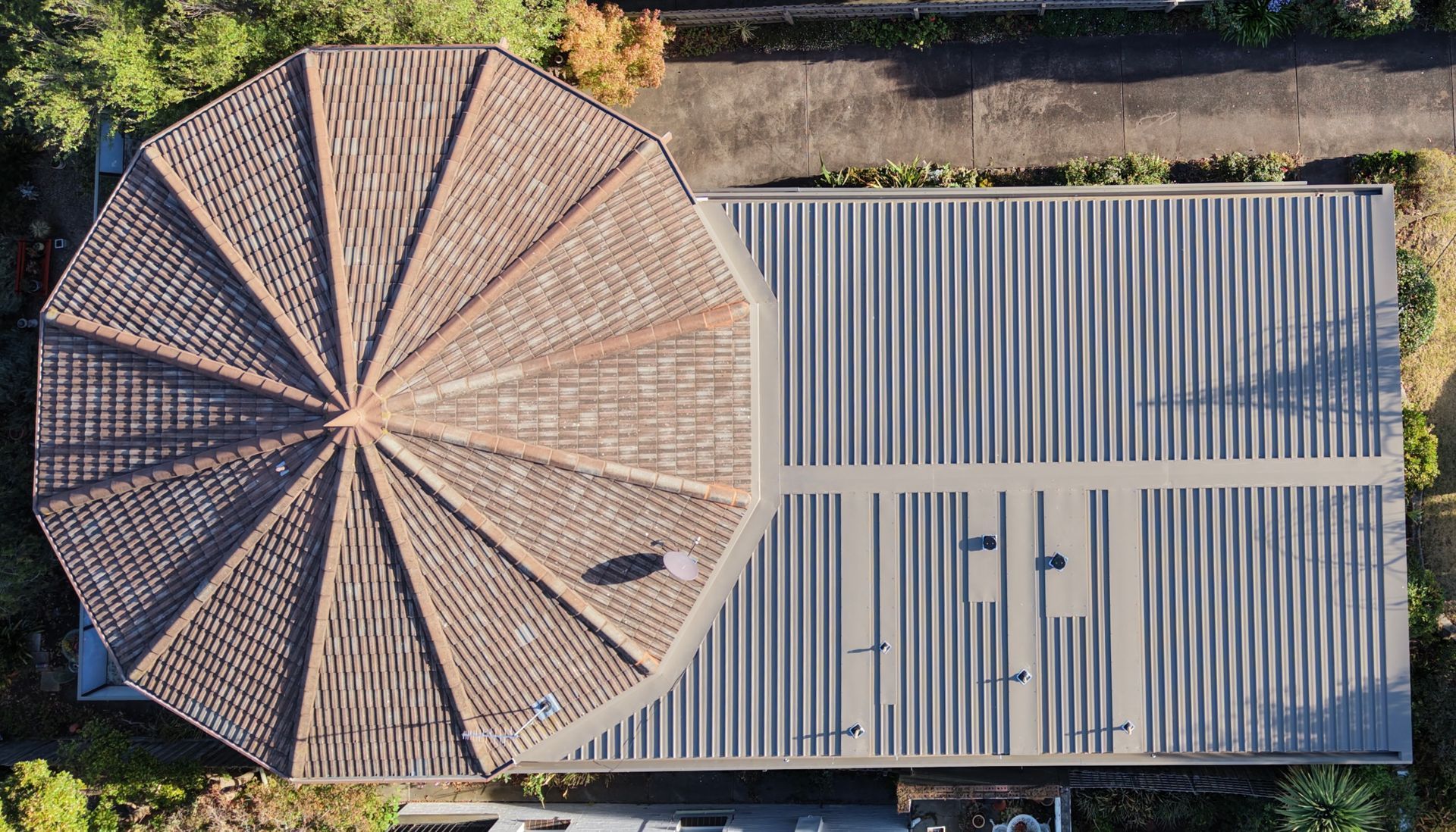Aerial view of a circular tiled roof beside a rectangular corrugated metal roof. — Hinch Plumbing In Breakwater, VIC