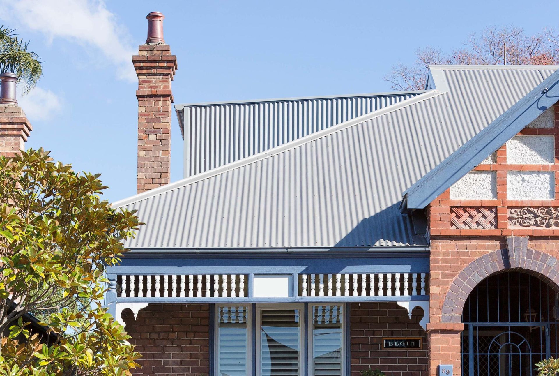 Brick house with a corrugated metal roof, chimney, and arched entrance under a clear blue sky — Hinch Plumbing In Breakwater, VIC