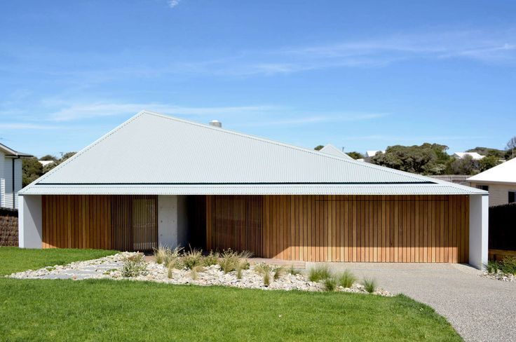 Modern single-story house with white roof, wood slat facade, and green lawn under a blue sky — Hinch Plumbing In Breakwater, VIC