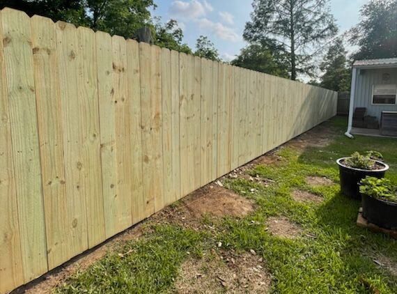 A wooden fence is sitting in the grass next to a house.