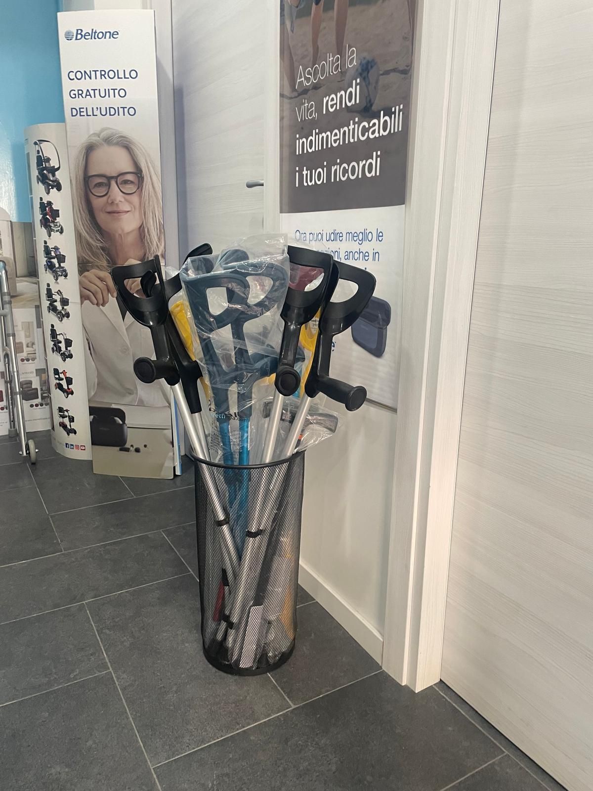 Un contenitore di metallo contiene diverse stampelle accanto a una porta bianca e a una pubblicità.