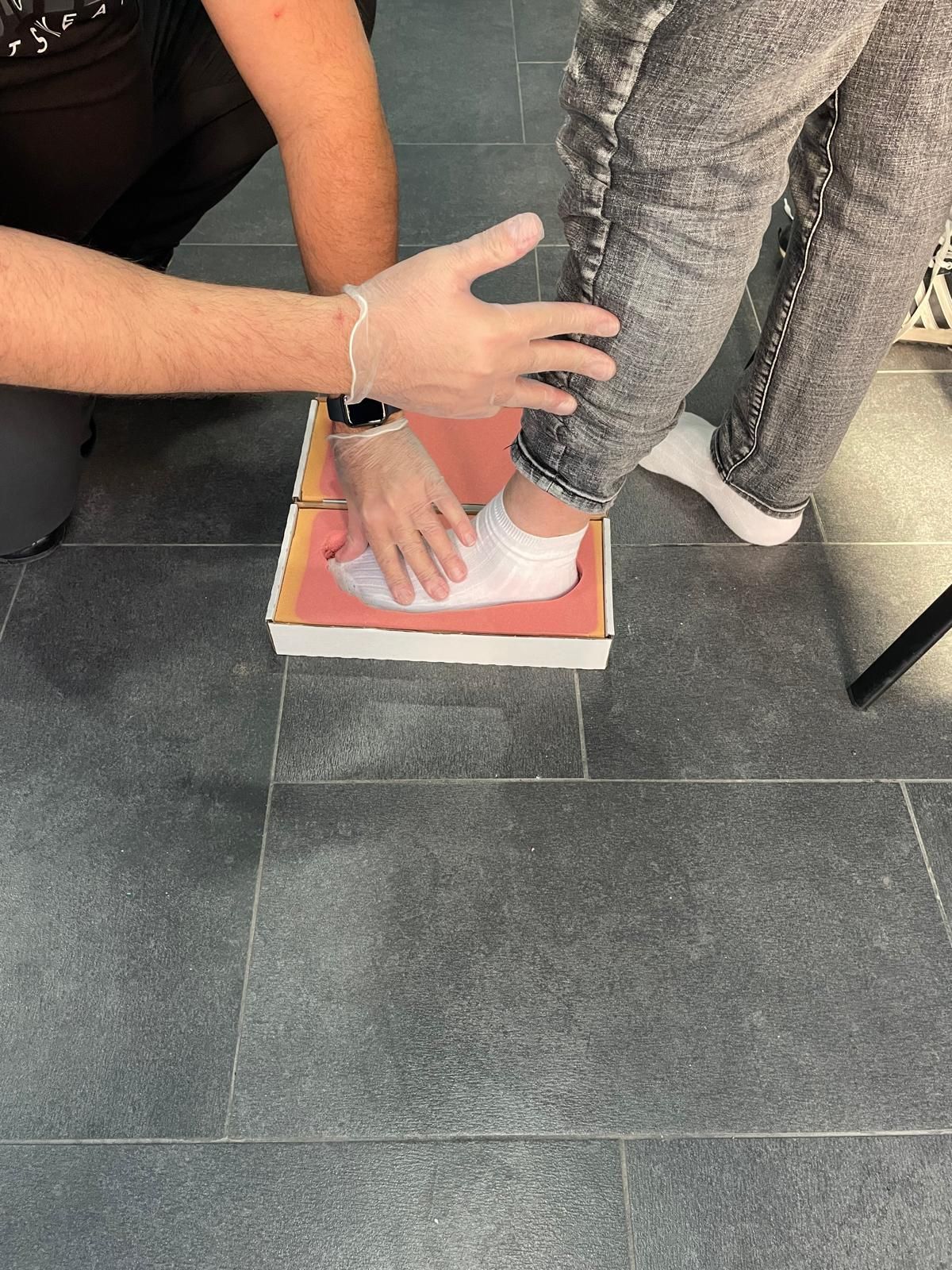 Il piede di una persona in una scatola, valutato dalla mano di qualcuno.