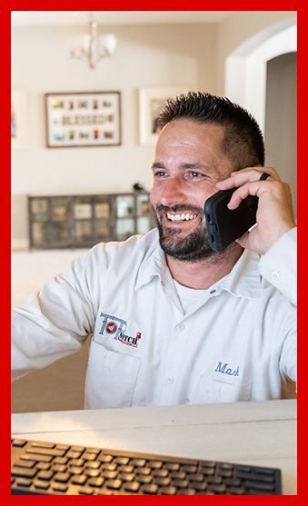 A Plumber in gilbert az is sitting at a desk talking on a cell phone.
