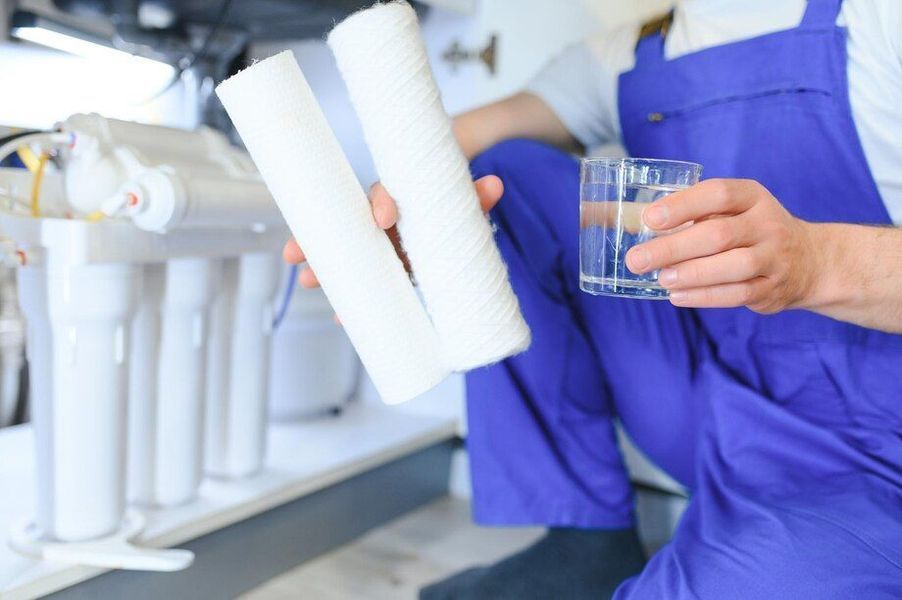 A person is holding a filter and a glass of water.