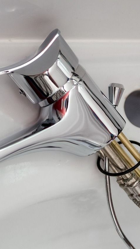 A man is fixing a faucet in a kitchen sink.