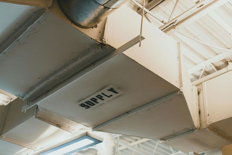 A section of industrial HVAC ductwork suspended from a ceiling, with the word