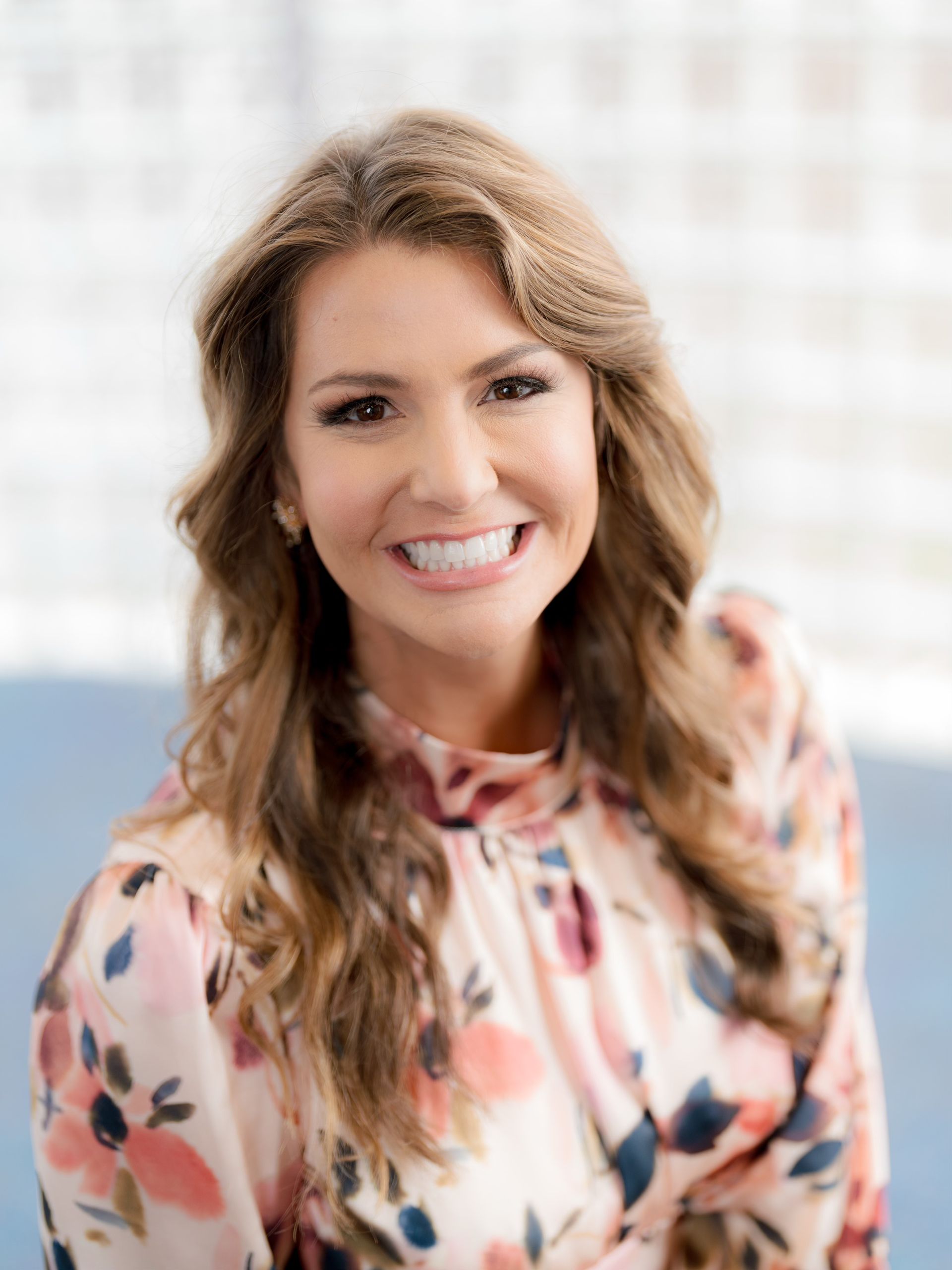 A woman in a floral shirt is smiling for the camera.