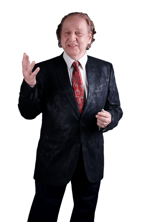 A person in a black patterned suit and red patterned tie gestures with one hand while standing against a white background.
