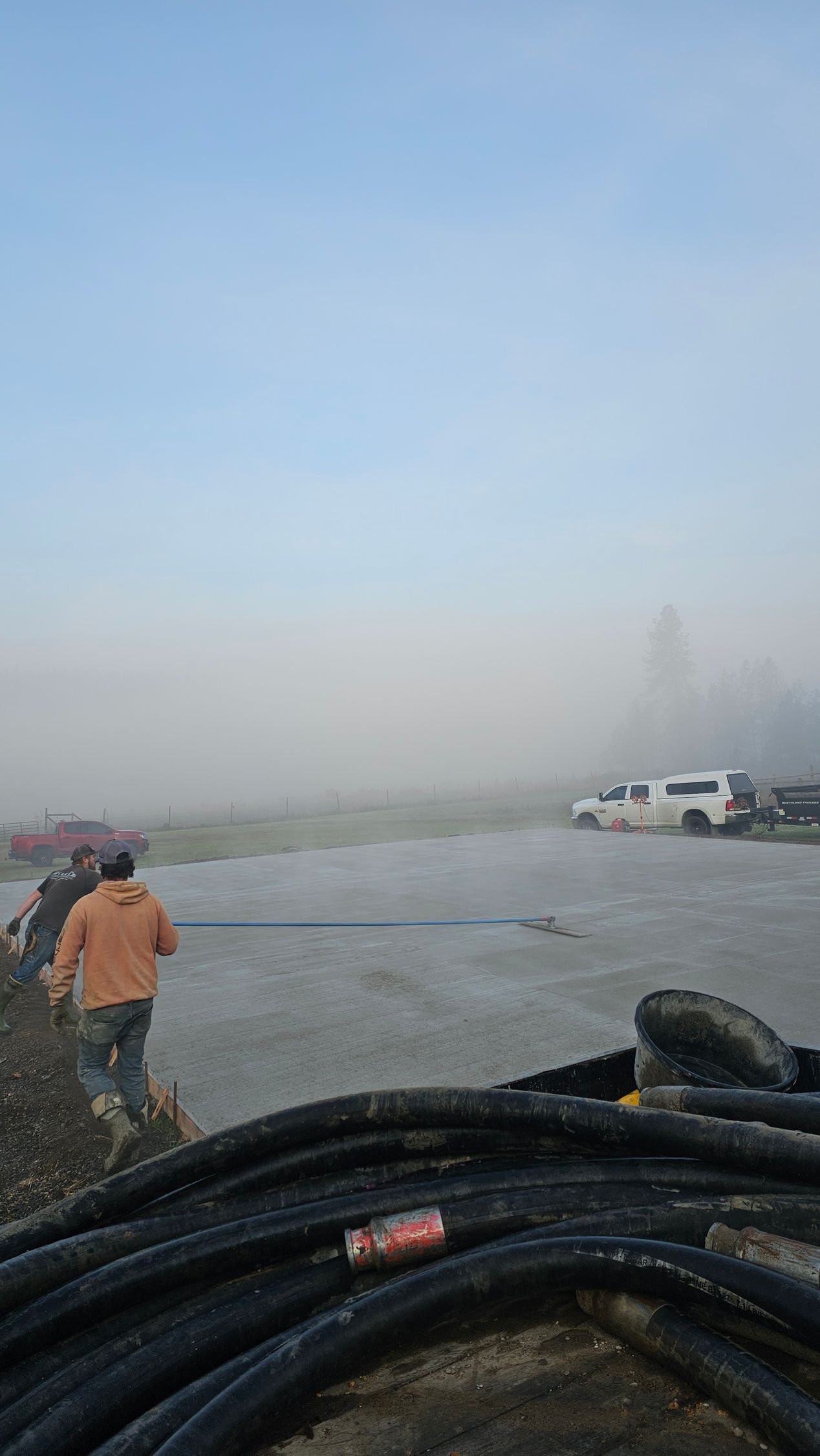 Bull float used to smooth large concrete slab during morning concrete job