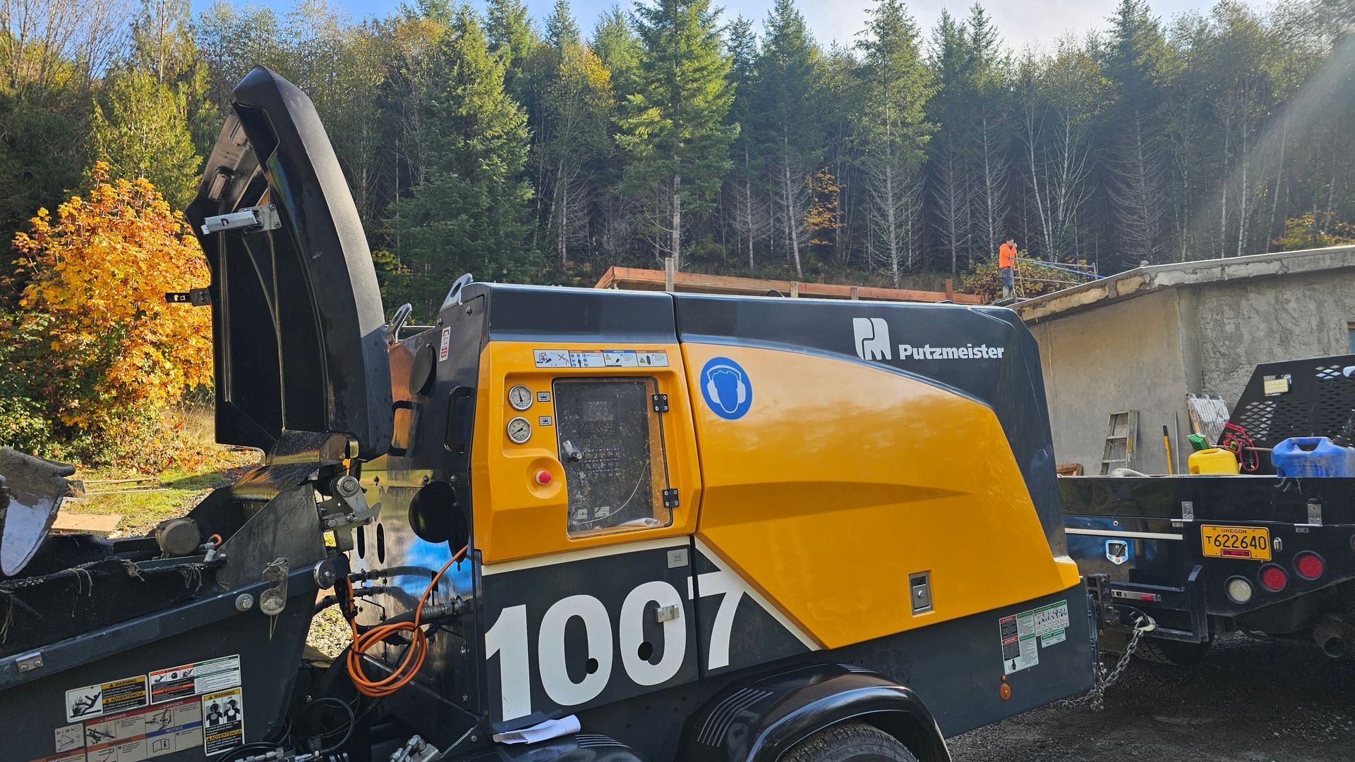 Putzmeister concrete pump trailer setup at rural construction site with scaffold