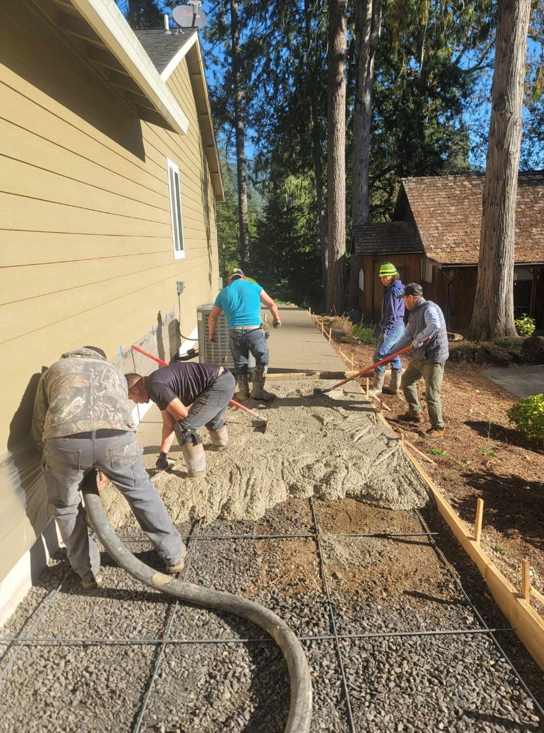 Crew pouring and smoothing concrete sidewalk on residential property