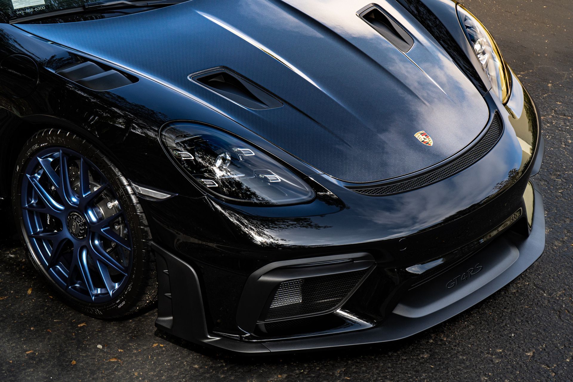 A black sports car with blue wheels is parked on the street