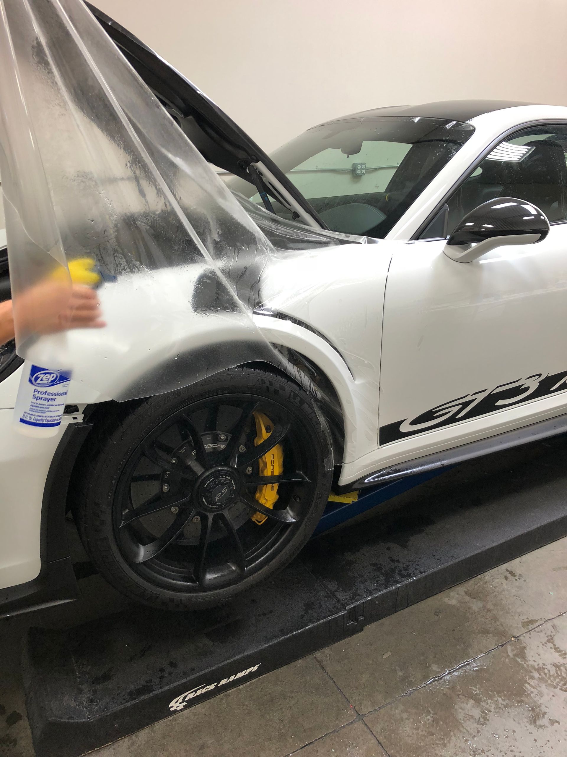 A person is applying protective film to the hood of a car.