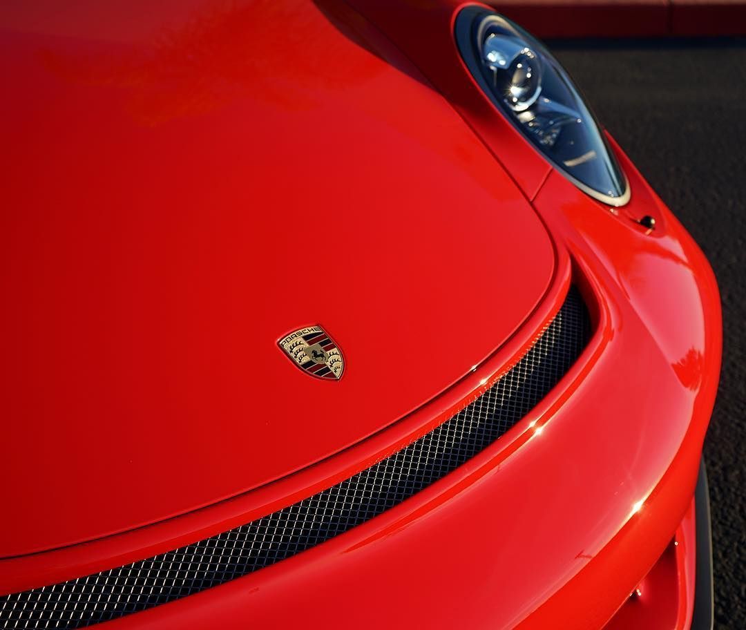 A red porsche car is parked on the street