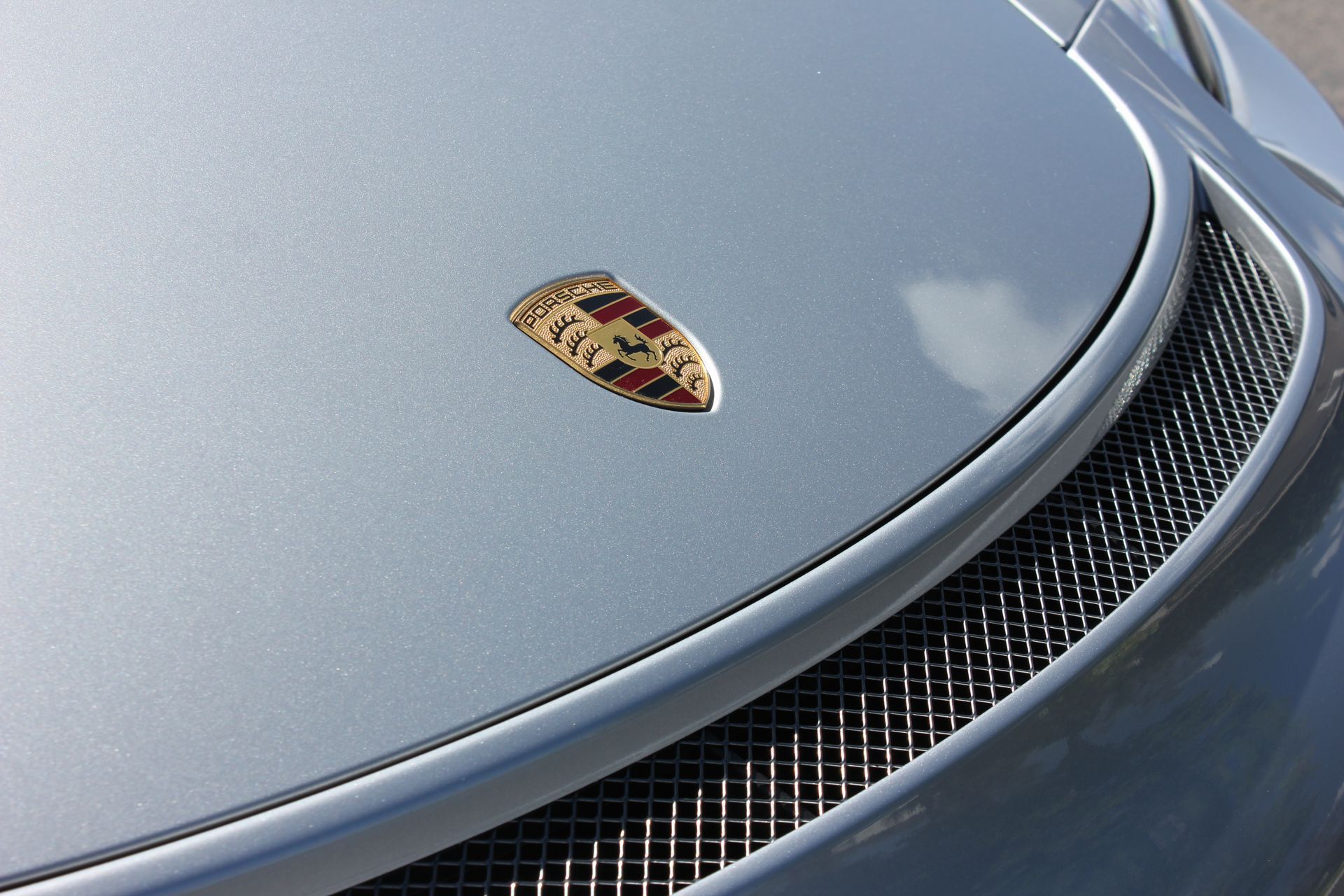The hood of a silver porsche with a crest on it