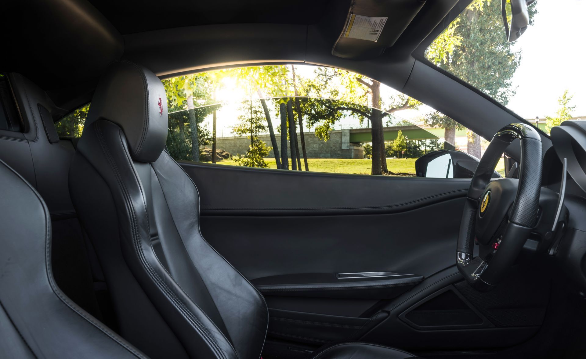 The inside of a ferrari sports car with the sun shining through the window.