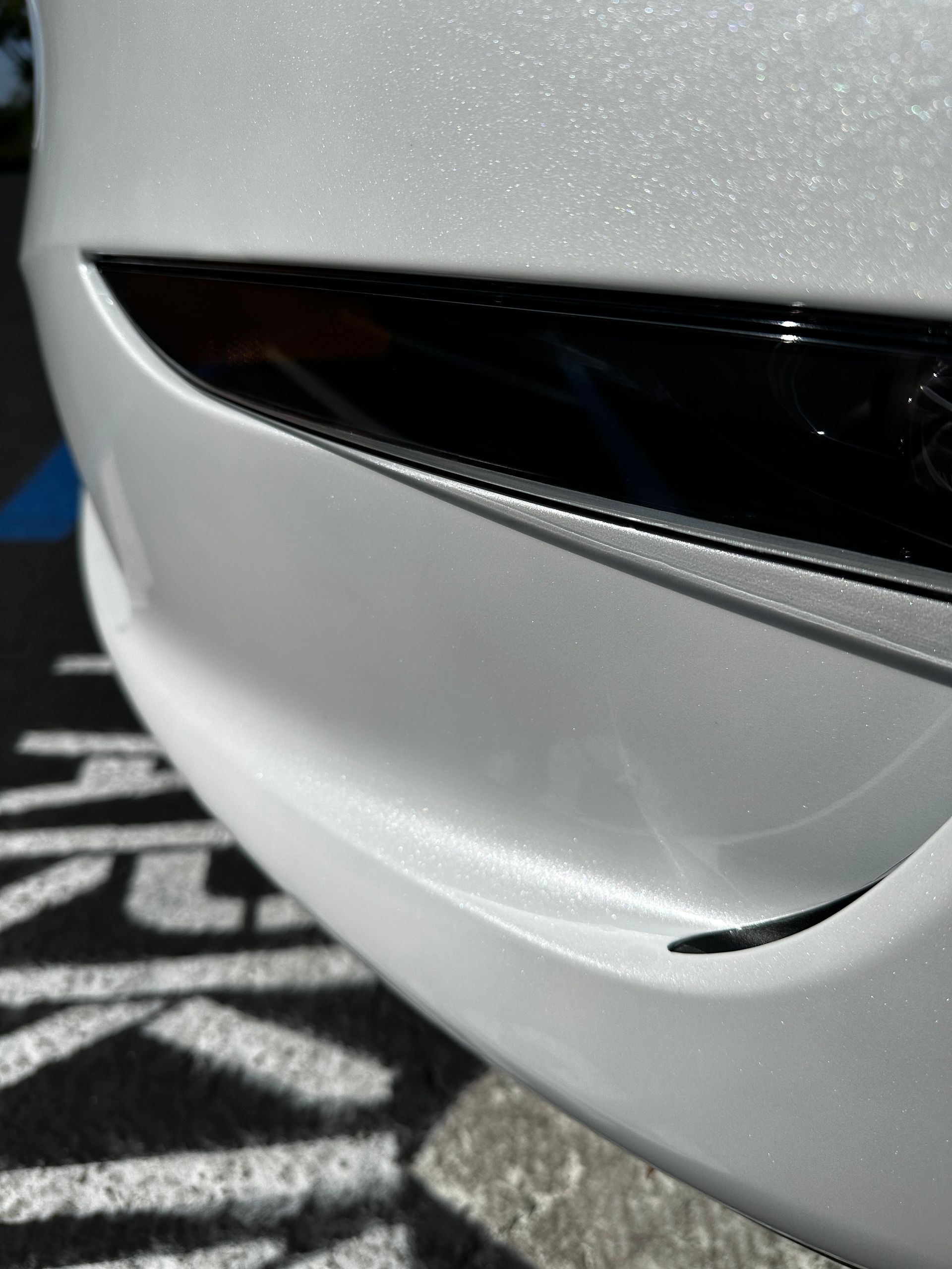 A white tesla model 3 is parked in a parking lot.