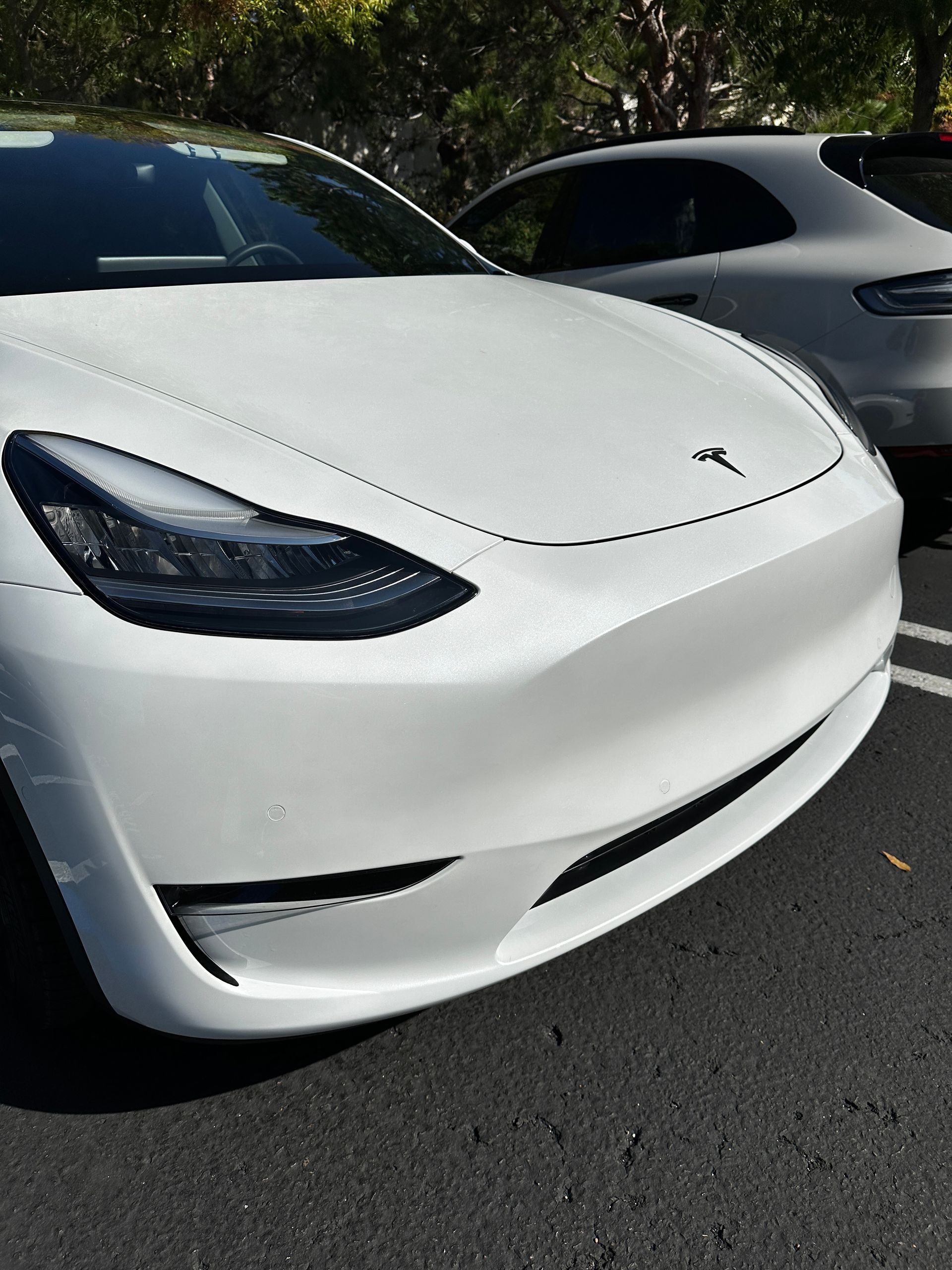 A white tesla model 3 is parked in a parking lot.