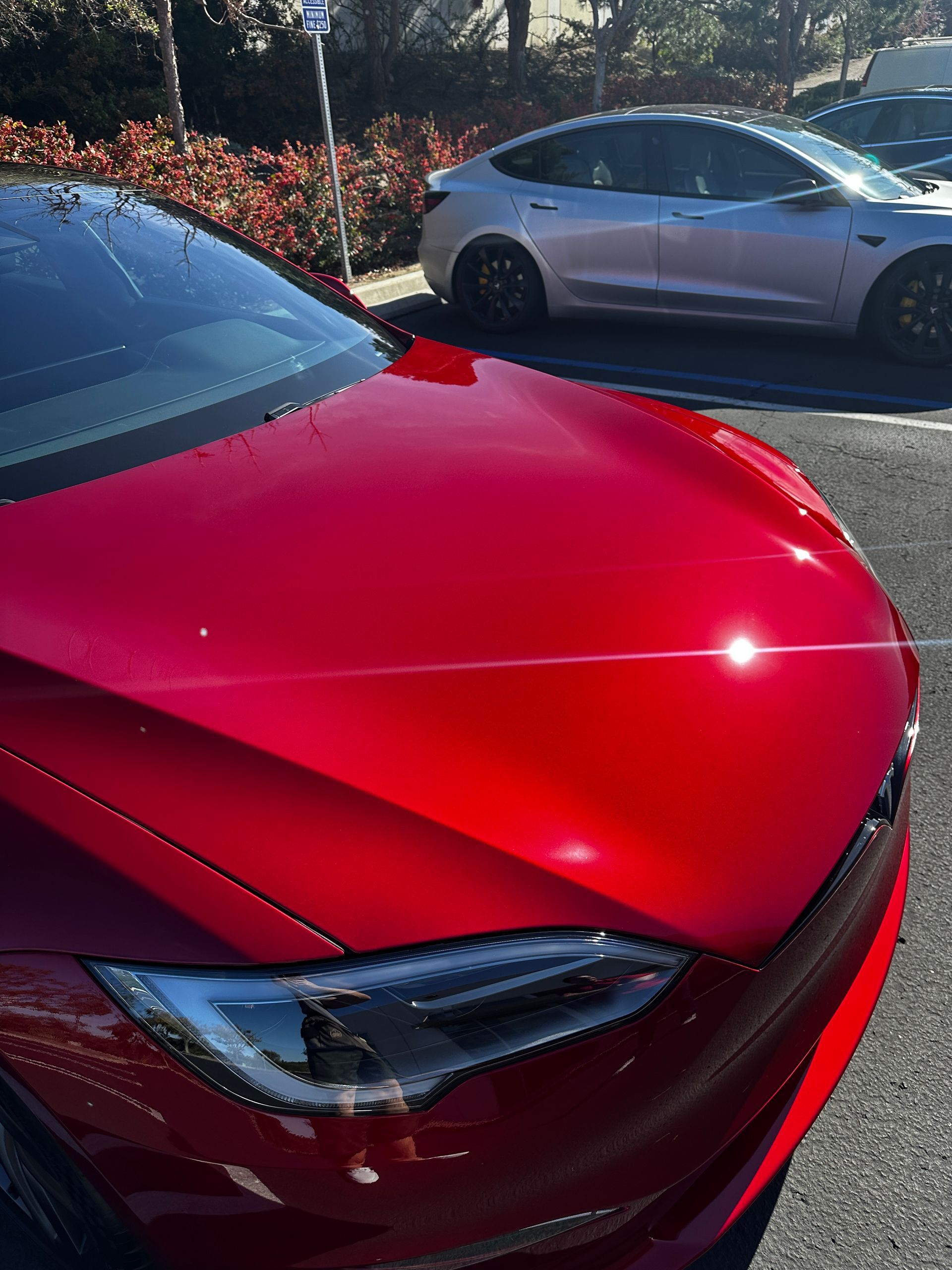 A red tesla model s is parked next to a white tesla model 3