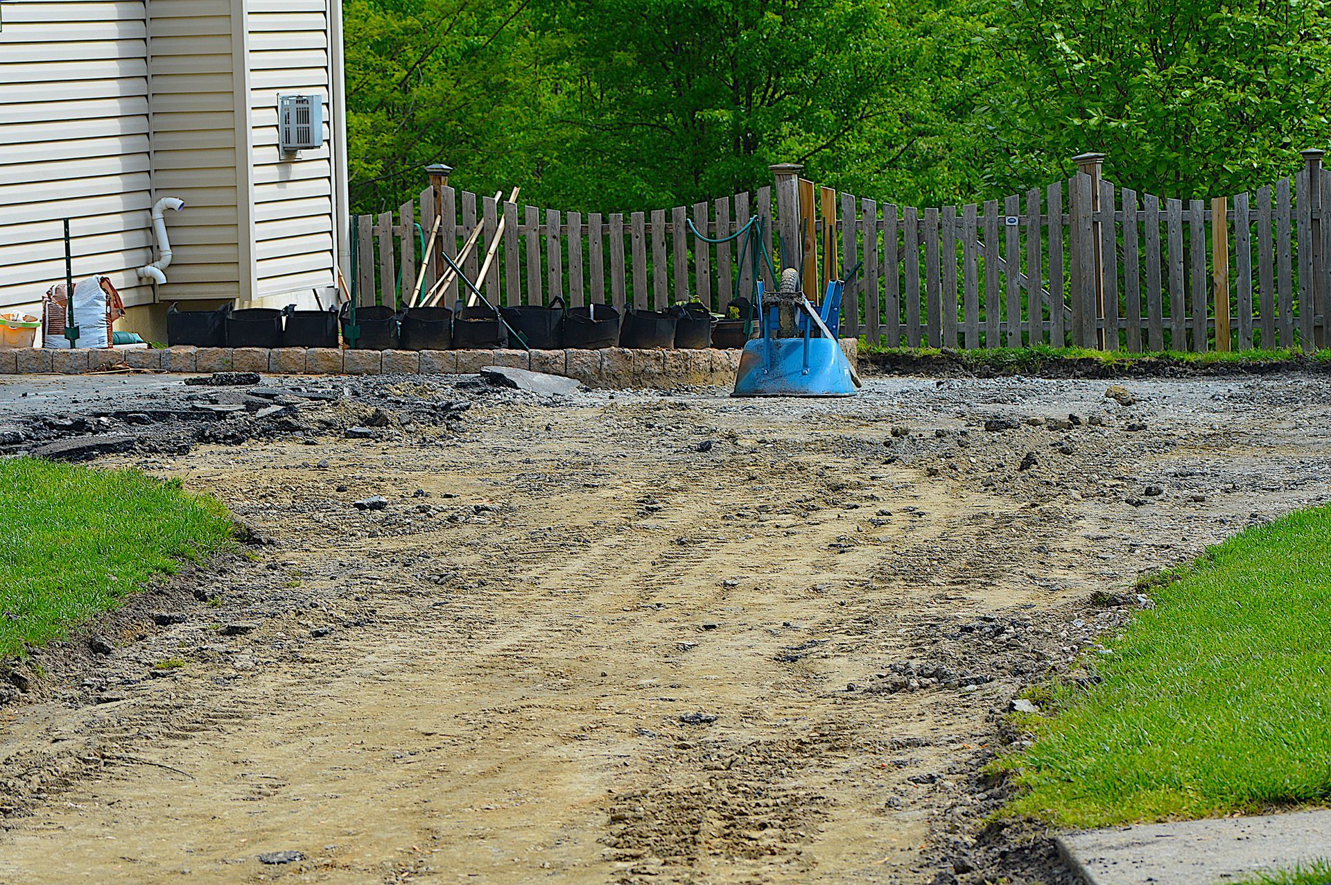 A dirt path leading to a house with a fence in the background