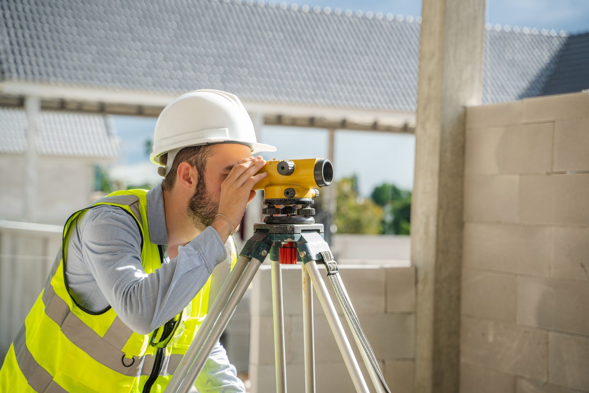 A construction worker is looking through a level on a tripod.