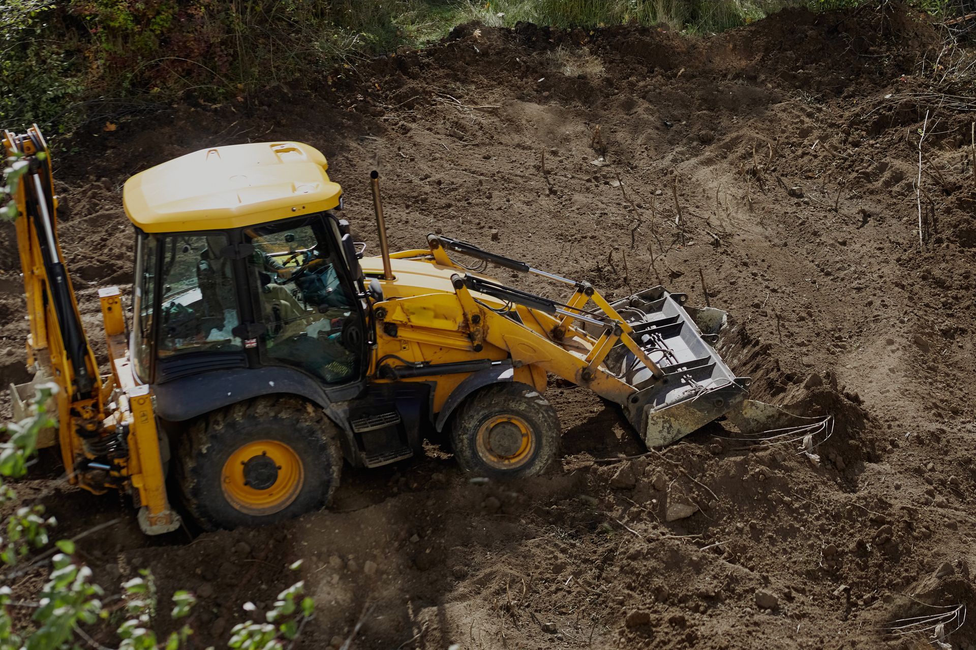 A yellow tractor is driving through a dirt field.
