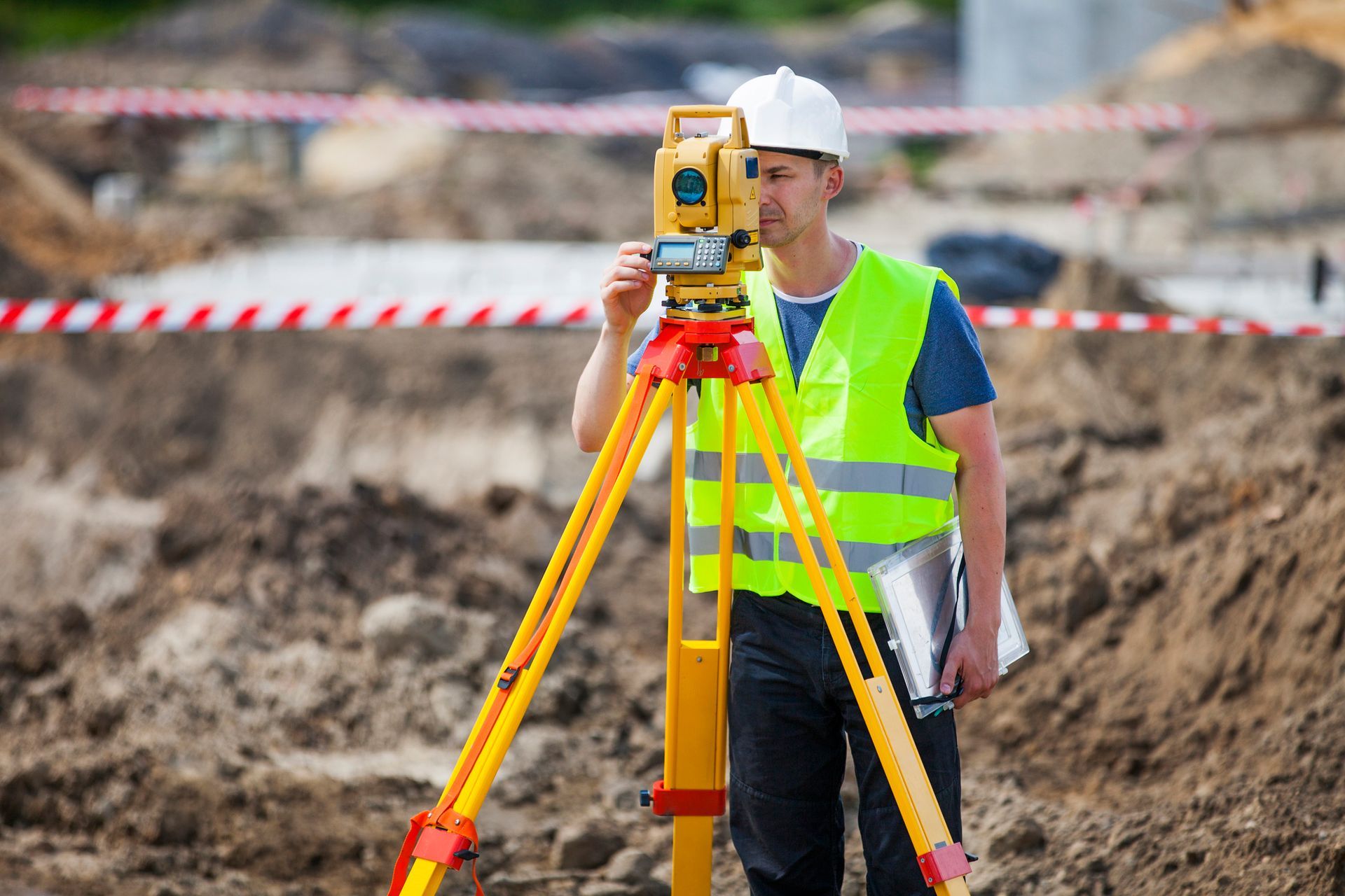 A construction worker is using a total station on a construction site.