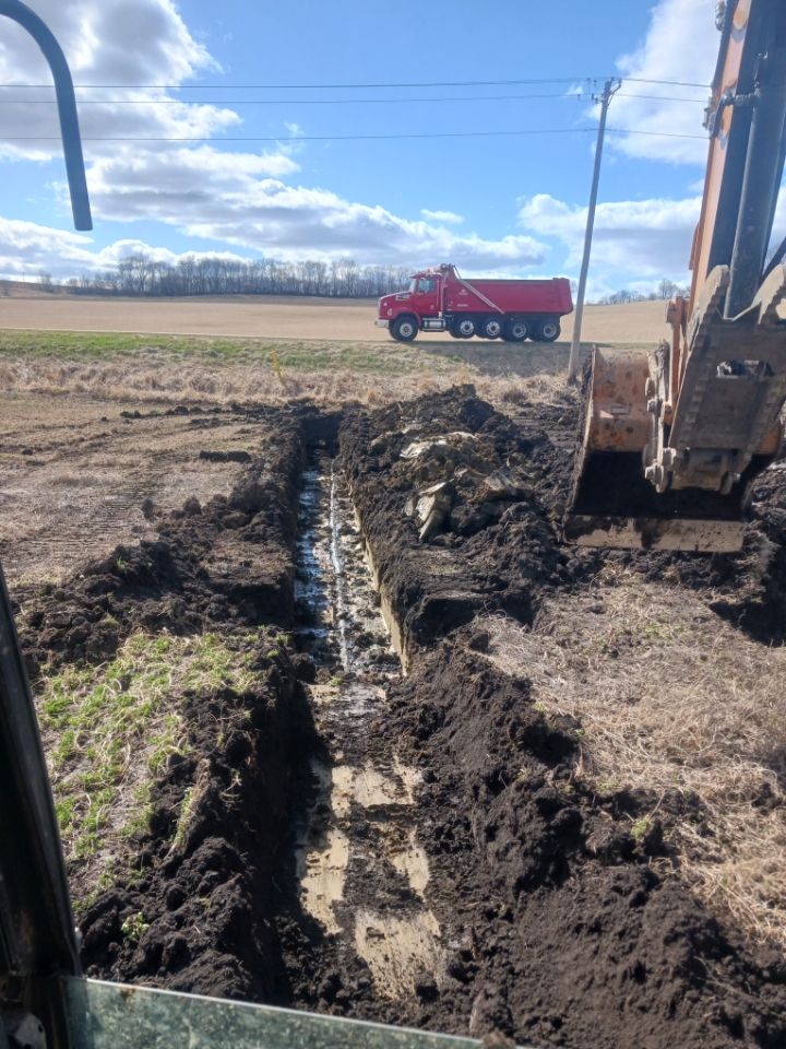 A person is digging a hole in the ground to install a drain pipe.
