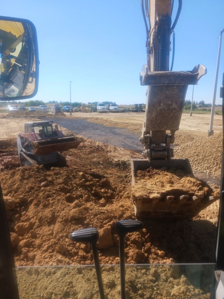 A man in a hard hat is standing in front of a bridge.