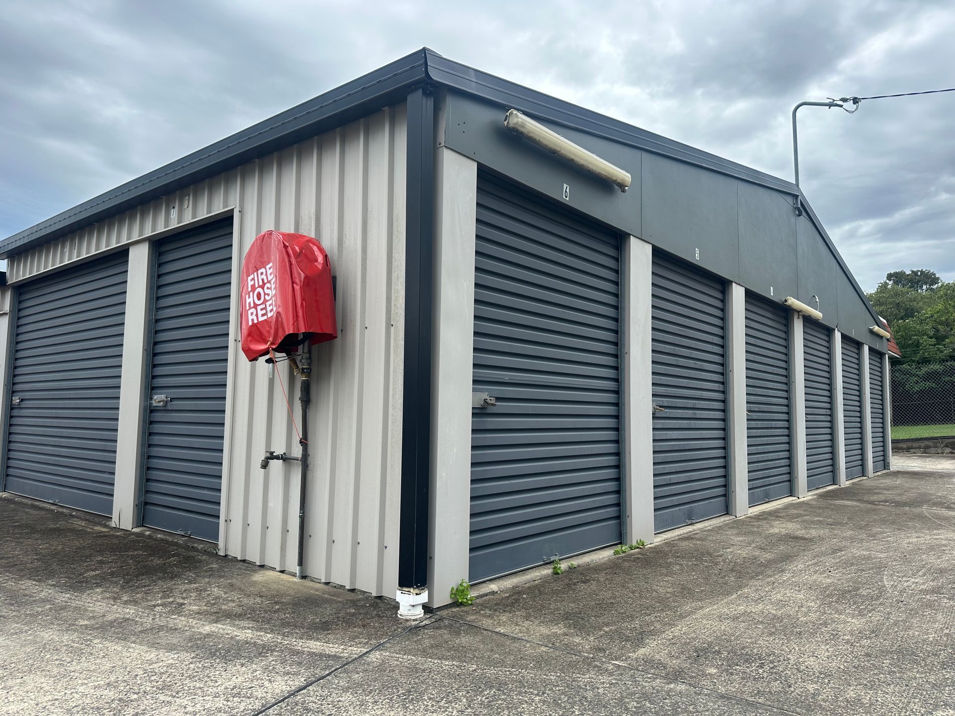 A row of garage doors with a red fire hydrant on the side of the building.— Coolabah Self Storage In Wingham, NSW