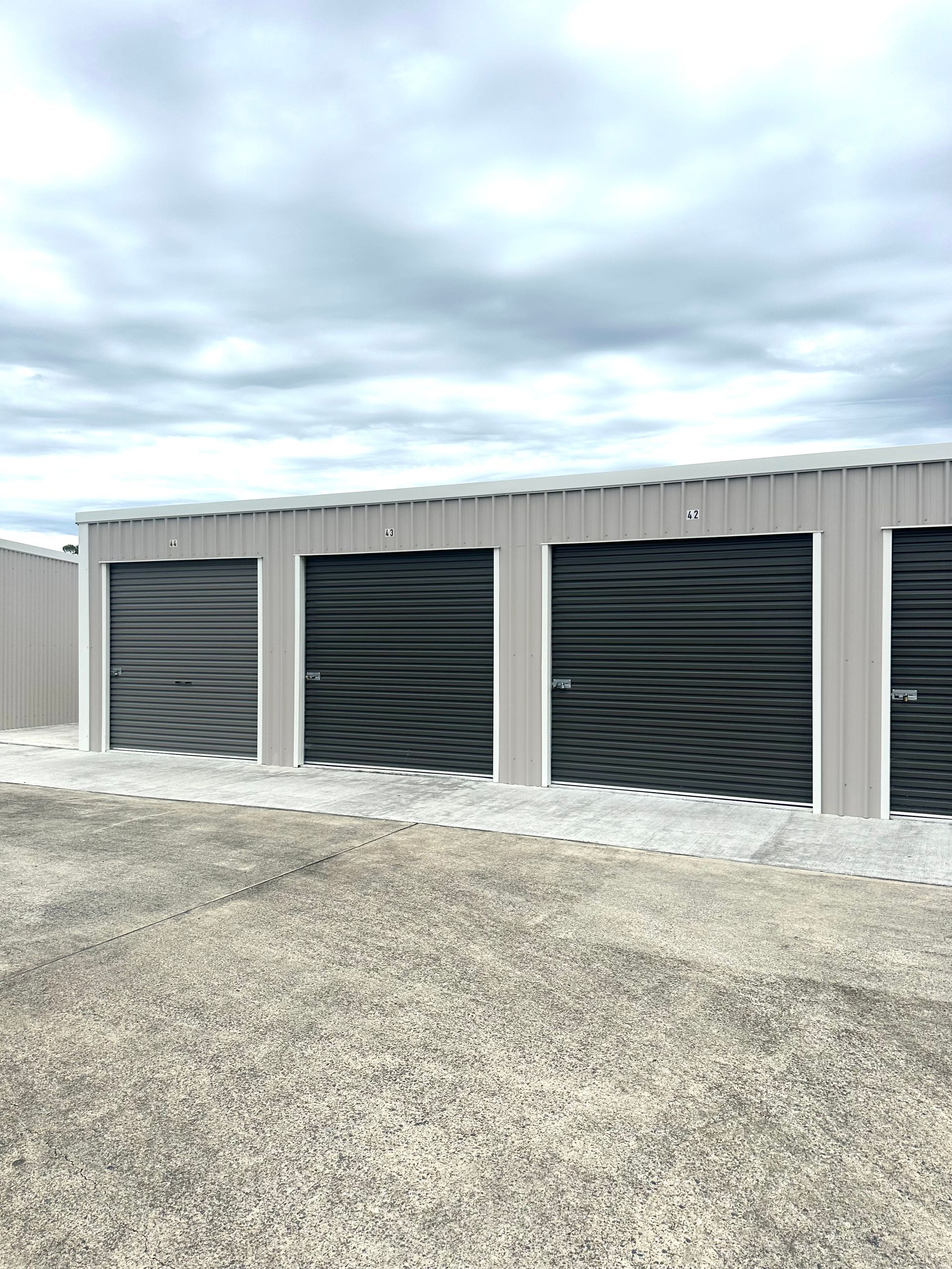 A row of storage units with black doors in a field.— Coolabah Self Storage In Old Bar, NSW