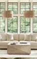 A bright living room with tall windows covered by striped roller shades and patterned floor-length curtains.